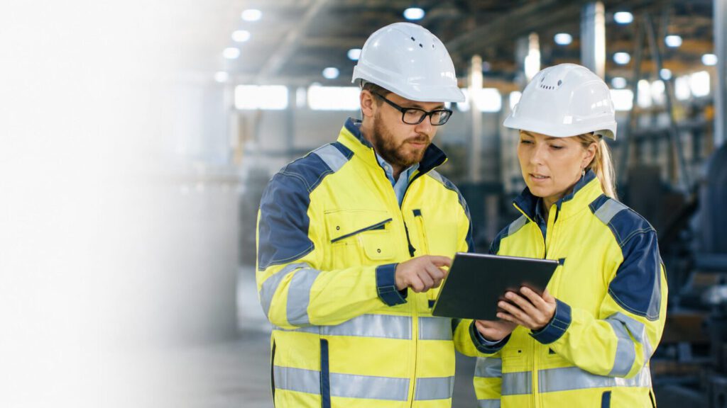 Beratung zur Arbeitssicherheit in einer Industriehalle mit Tablet
